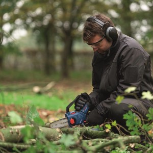Bosch Akku-Astsäge GKE 18V-15 Solo im Einsatz: Mann sägt Äste im Garten mit der Akku-Kettensäge.