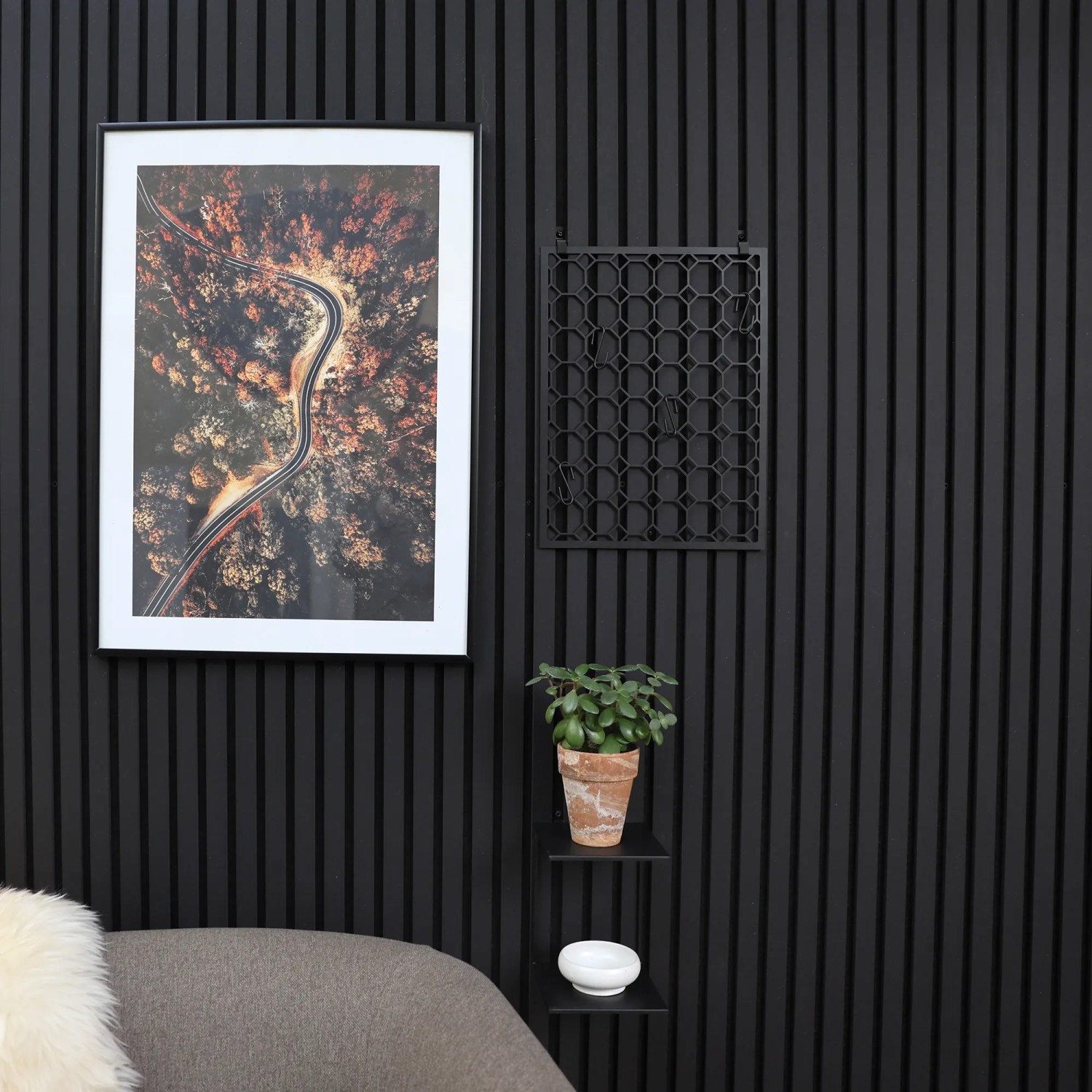 Schwarzes Denpanels Doppelregal mit Deko an Akustikpaneelwand.