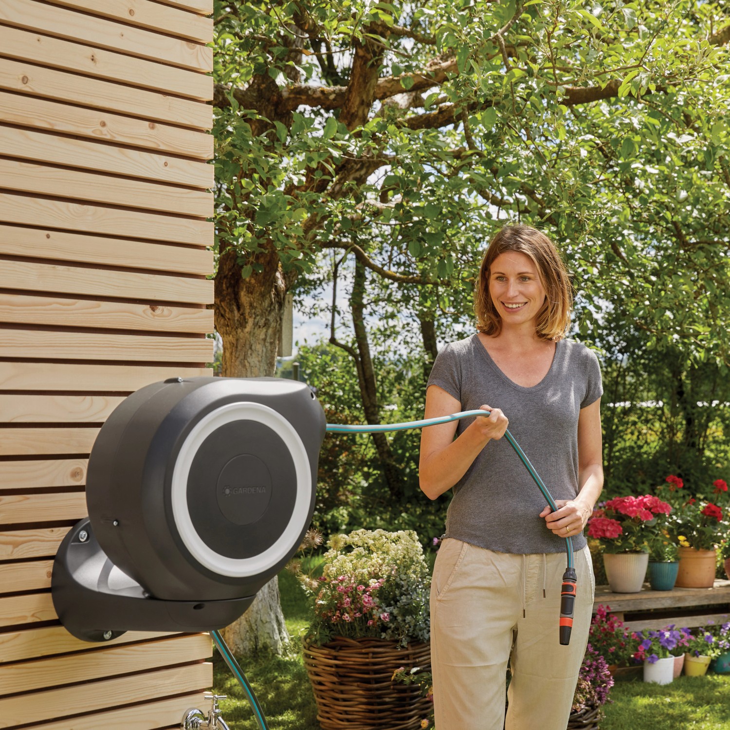 Gardena Wand-Schlauchbox RollUp S mit 15m Schlauch im Einsatz, Frau hält Schlauch in der Hand.