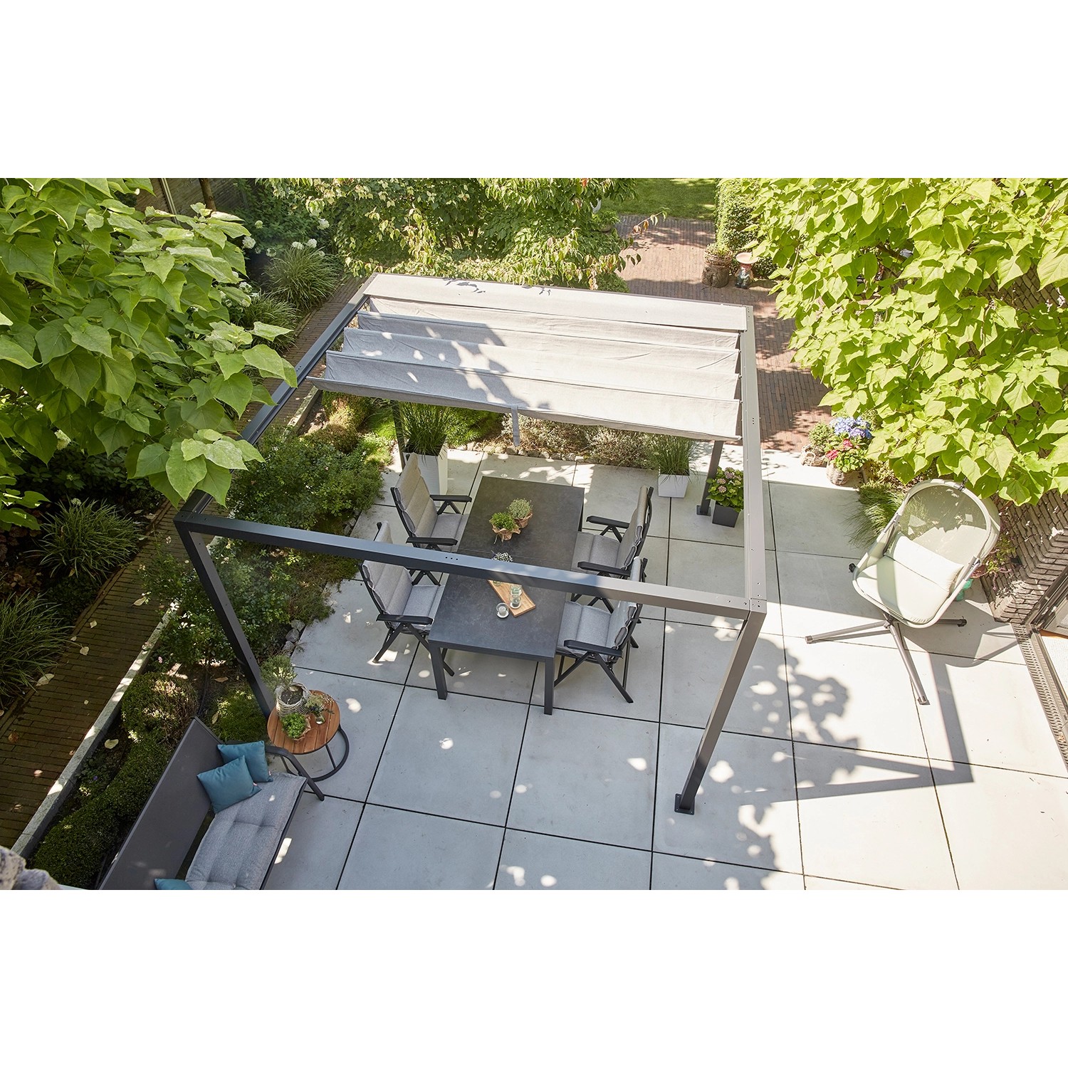 Siena Garden Pergola Schattenmanufaktur mit Faltdach und Gartenmöbeln in Anthrazit.