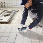 Handwerker mit Bosch Professional Multicutter GOP 55-36 beim Fliesenschneiden.