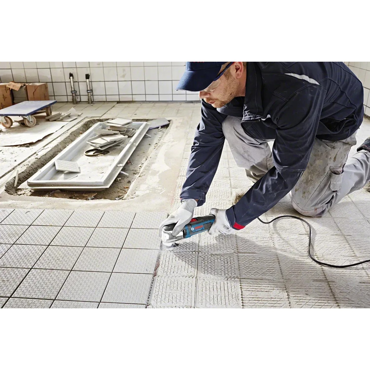 Handwerker mit Bosch Professional Multicutter GOP 55-36 beim Fliesenschneiden.
