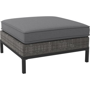 Grauer Lounge-Hocker Alridge aus Polyrattan mit Auflage, geeignet als Fußablage oder Sitzgelegenheit.