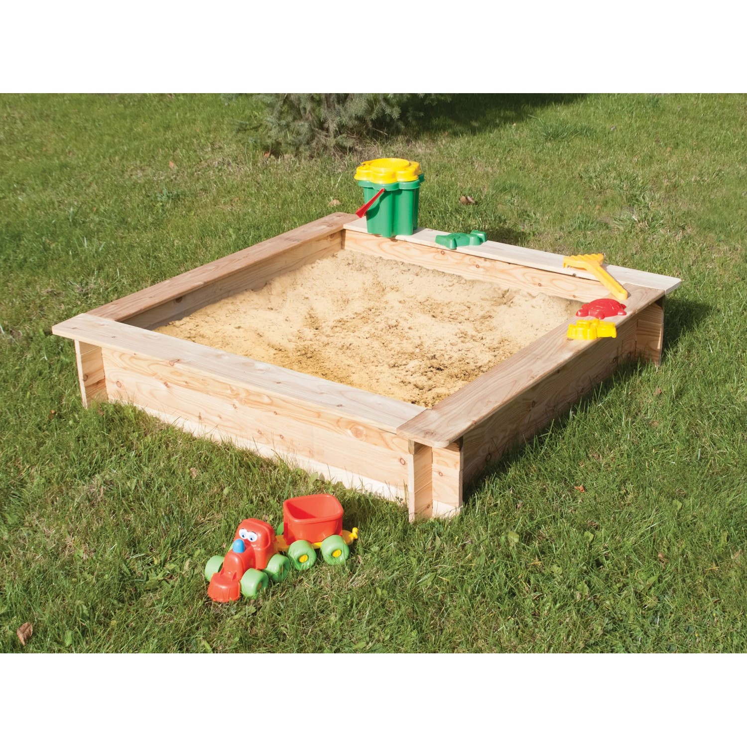 Rechteckiger Sandkasten aus Fichtenholz (120x120 cm) mit Spielzeug auf einer grünen Wiese.