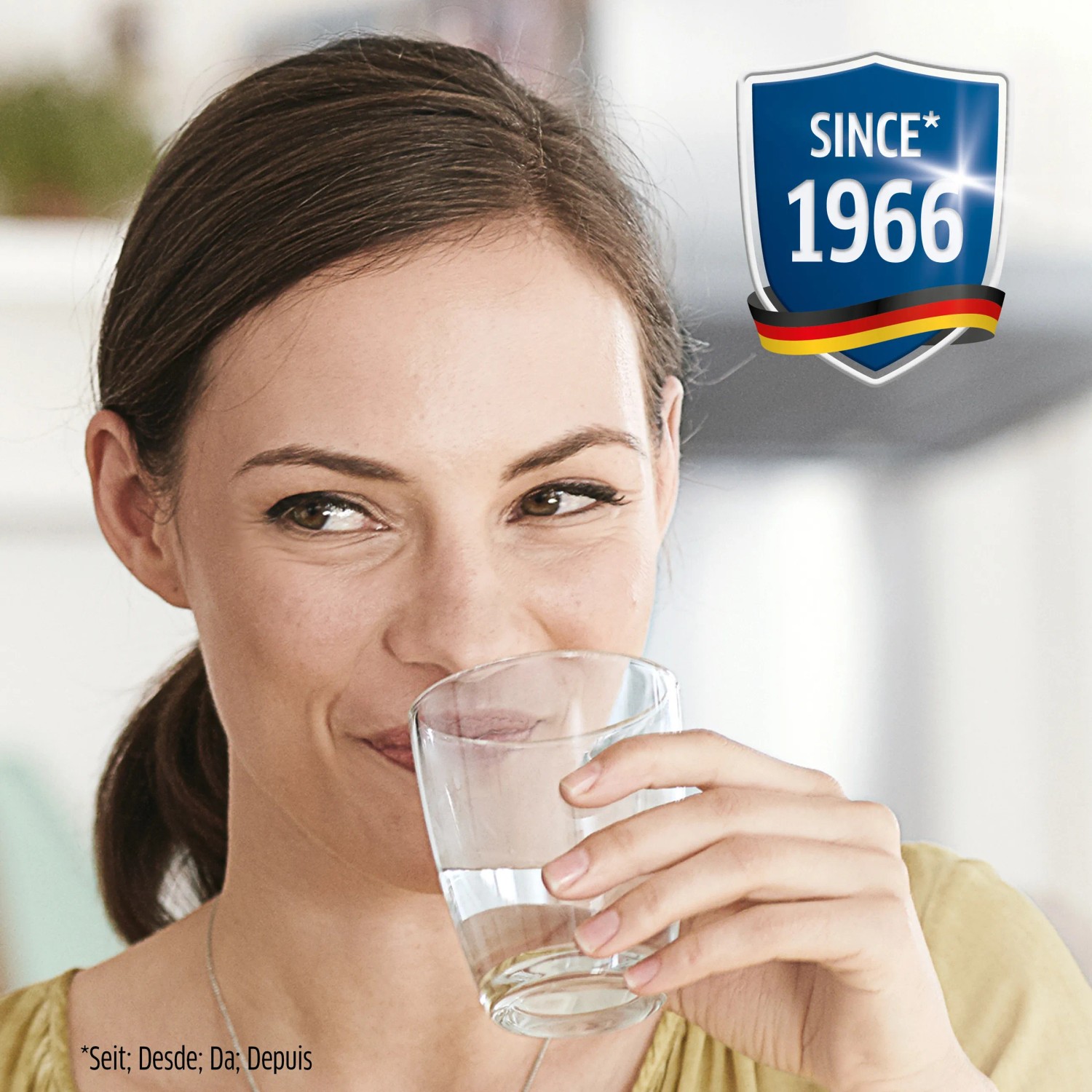 Frau trinkt gefiltertes Wasser aus Glas. Brita Wasserfilter Kartusche für reines Wasser.