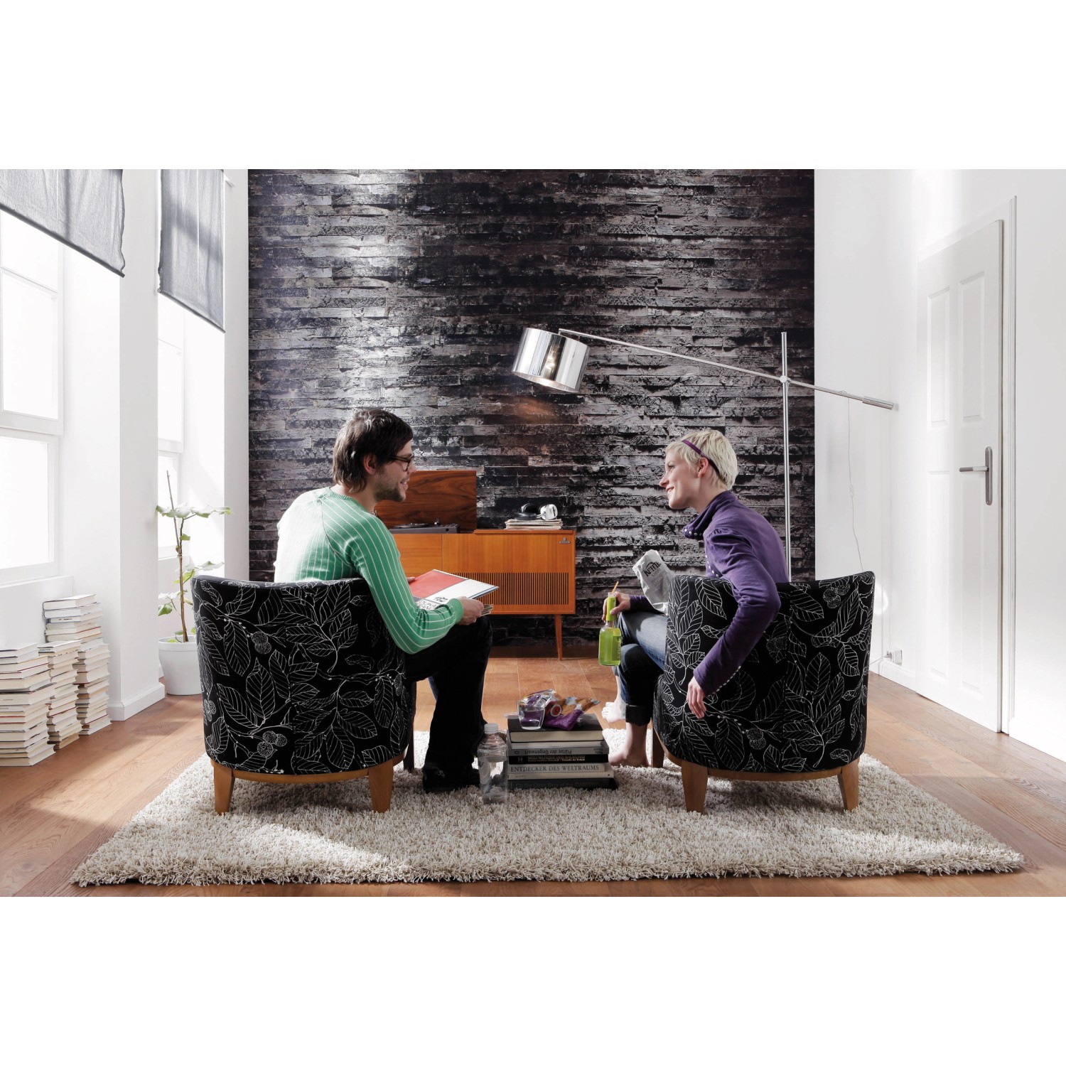 Wohnraum mit Komar Fototapete Birkenrinde als Wanddeko, zwei Personen sitzen in Sesseln.