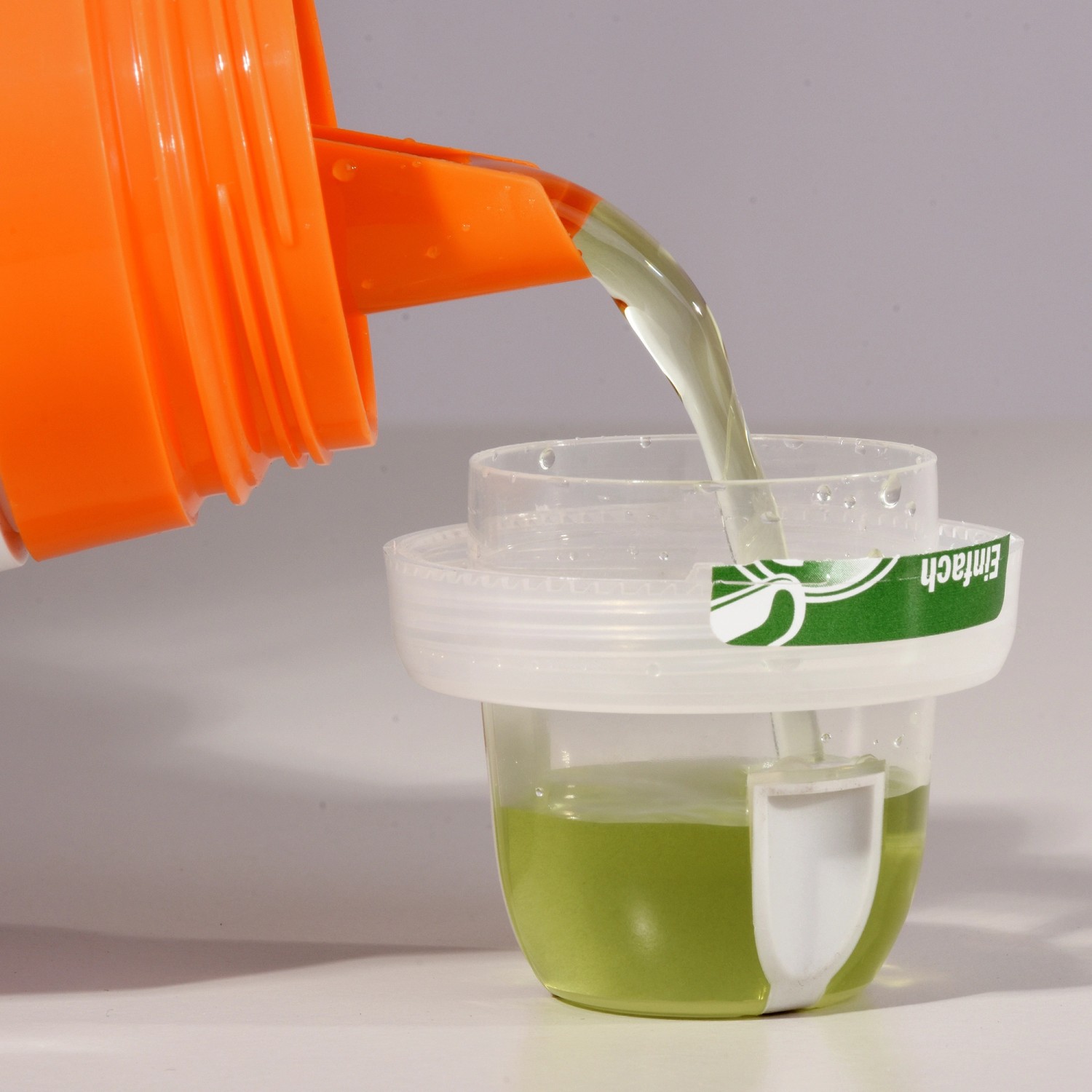 Dosierung von Compo Kakteendünger aus einer orangefarbenen Flasche in eine Messkappe.