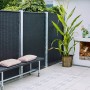 Schwarzer Sichtschutzzaun aus Polyrattan (115x170cm) im Garten mit Bank und Deko.
