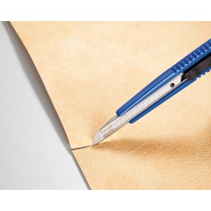 LUX Cuttermesser (9 mm) mit blauem Kunststoffgehäuse schneidet beiges Material.