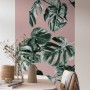 Komar Vlies Fototapete Monstera Rosé, 100x250 cm, mit tropischen Blättern an rosafarbener Wand.