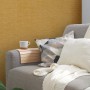 Gelbe Vliestapete mit organischem Muster, glänzend und strukturiert, an einer Wand im Wohnzimmer.