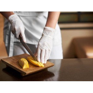 Hände mit weißen Einmalhandschuhen schneiden Mango auf Holzbrett. Latexfreie Handschuhe Gr. M.