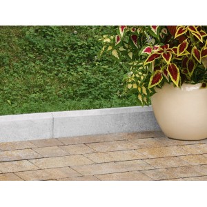 Grauer Rasenkantenstein (5x30x100 cm) zwischen Rasen und Pflaster, neben einem Topf mit Pflanze.