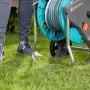 Gardena Schlauchwagen CleverRoll M mit 20m Schlauch auf Rasen. Gartenschlauchwagen-Set in Türkis und Grau.