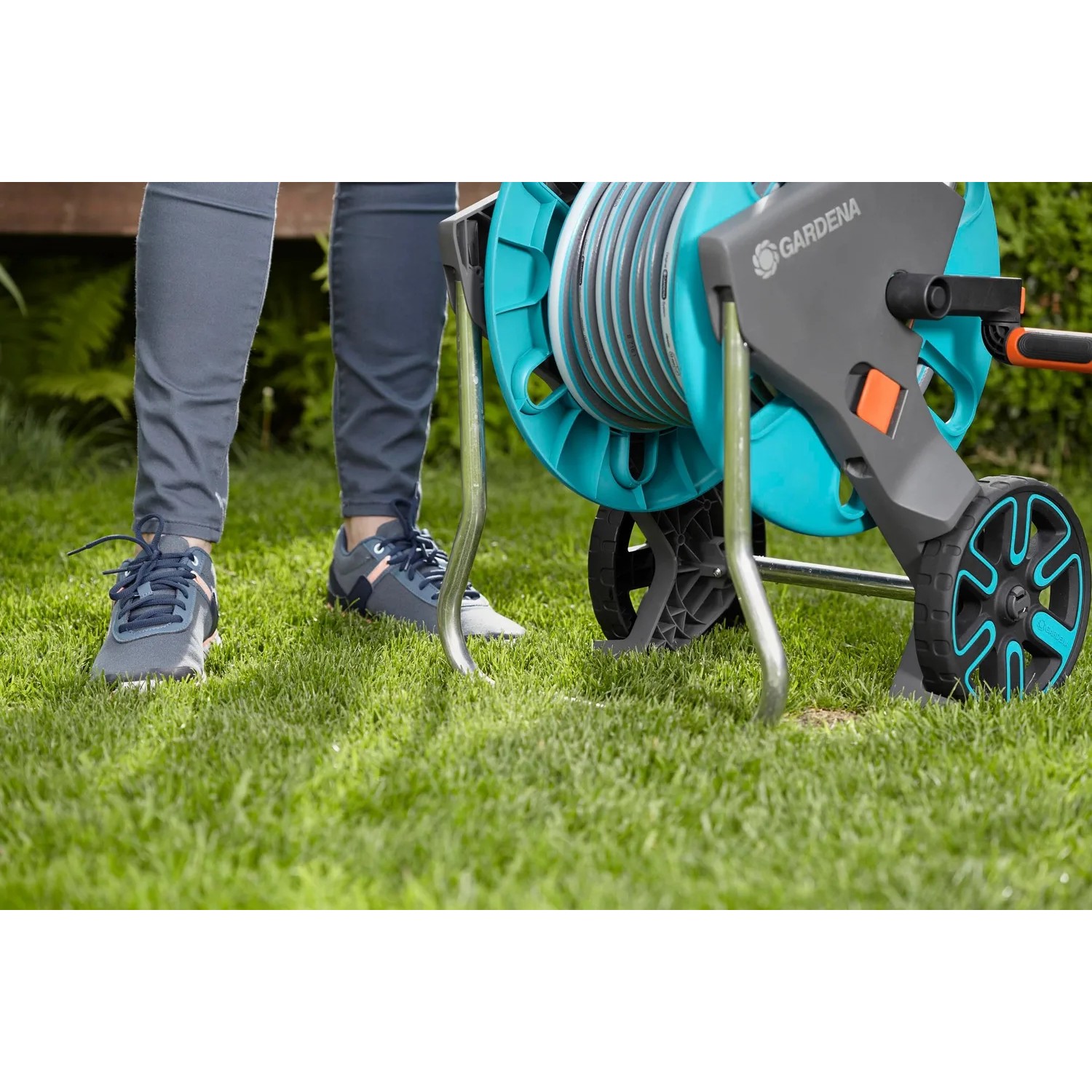Gardena Schlauchwagen CleverRoll M mit 20m Schlauch auf Rasen. Gartenschlauchwagen-Set in Türkis und Grau.
