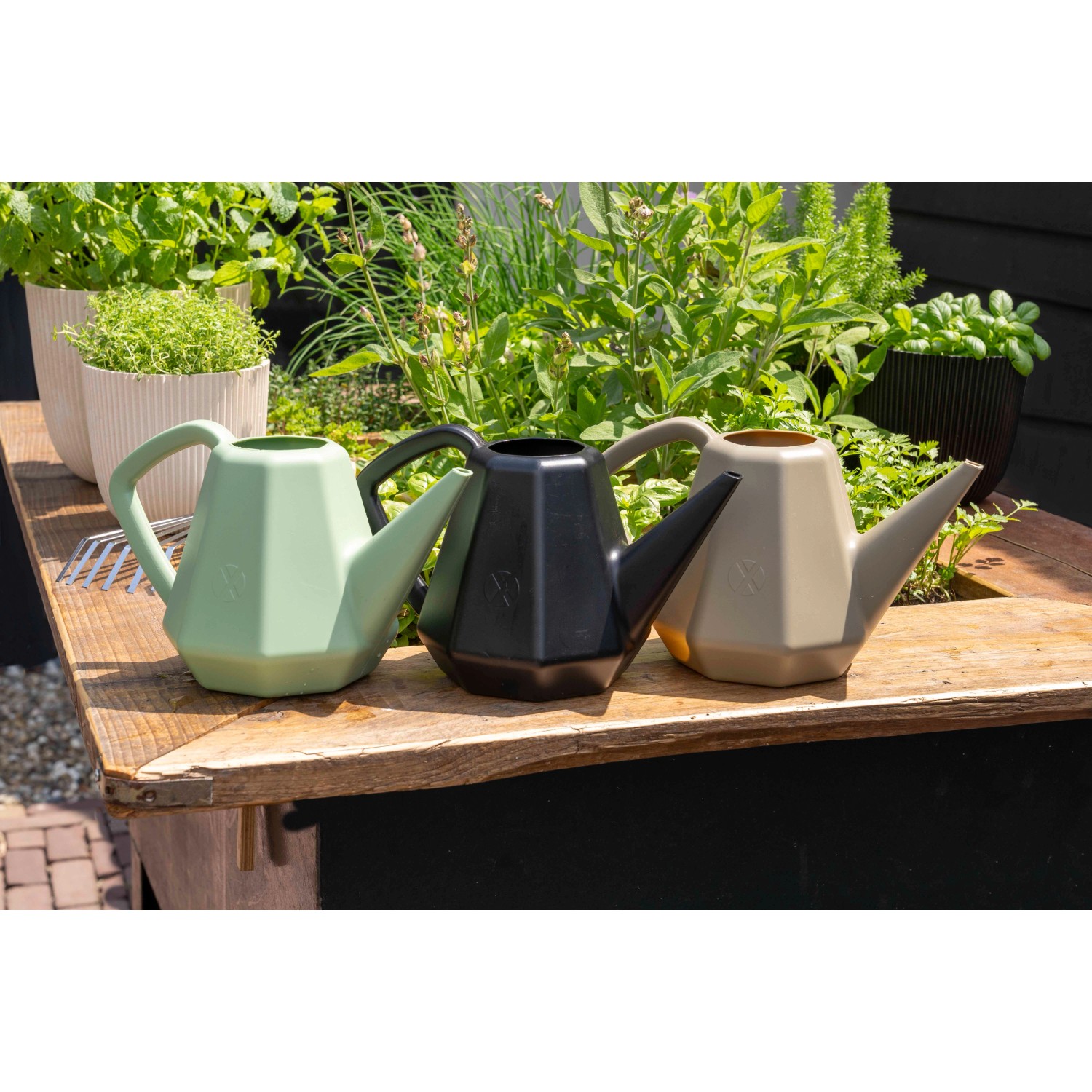 Capi Gießkanne Doppio Xala Groove, 2 l, olivgrau, schwarz und beige, auf einem Holztisch.