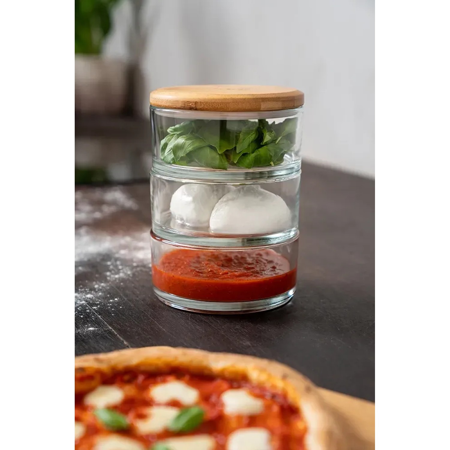 Ooni Stapelgefäß-Set aus Glas mit Bambusdeckel, gefüllt mit Zutaten für Pizza.