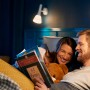 Paar liest im Bett unter Philips Hue White E14 LED Lampen. Smarte Beleuchtung mit Bluetooth.