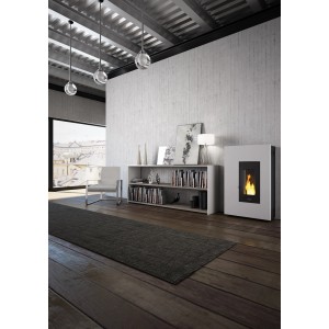 Weißer PEGASO Pelletofen Madison 5,3 kW im modernen Wohnraum mit Regal und Sessel.