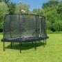 Rechteckiges, grünes EXIT Allure Classic Gartentrampolin 244x427 cm mit Sicherheitsnetz im Garten.