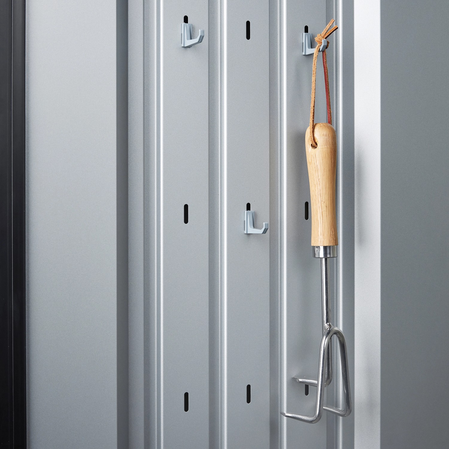 Innenansicht des silbernen Biohort Romeo Gartenschranks mit Haken und Gartengerät.