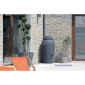 Anthrazitfarbene Waterform Regentonne Aquacan 210 l mit Deckel und zwei Anschlüssen vor Hauswand.