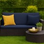 Marineblaues Gartensofa mit gelbem Zierkissen, Teil eines Sets für Polyrattan Möbel.