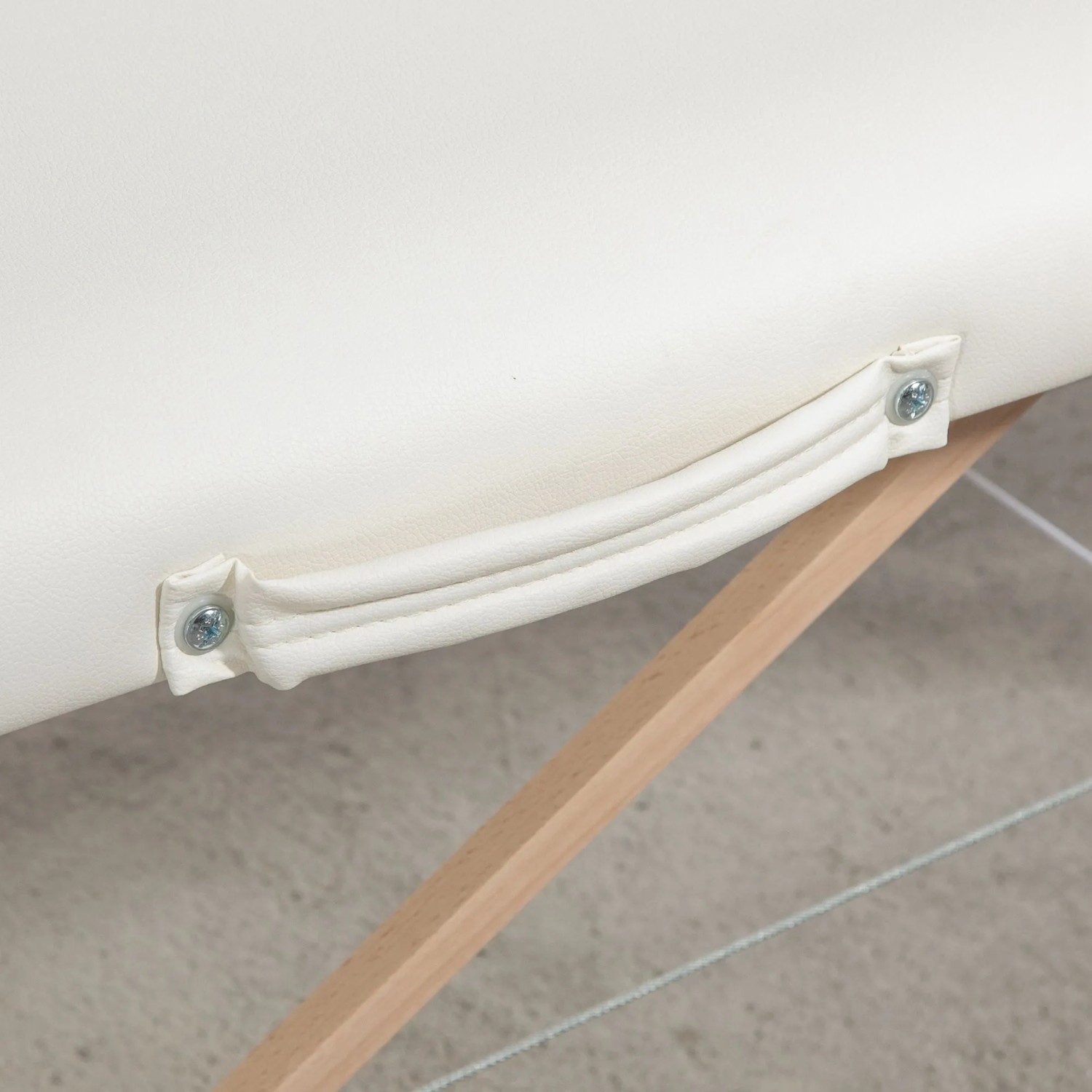 Cremeweißer Tragegriff an der klappbaren Massageliege aus PVC und Holz.