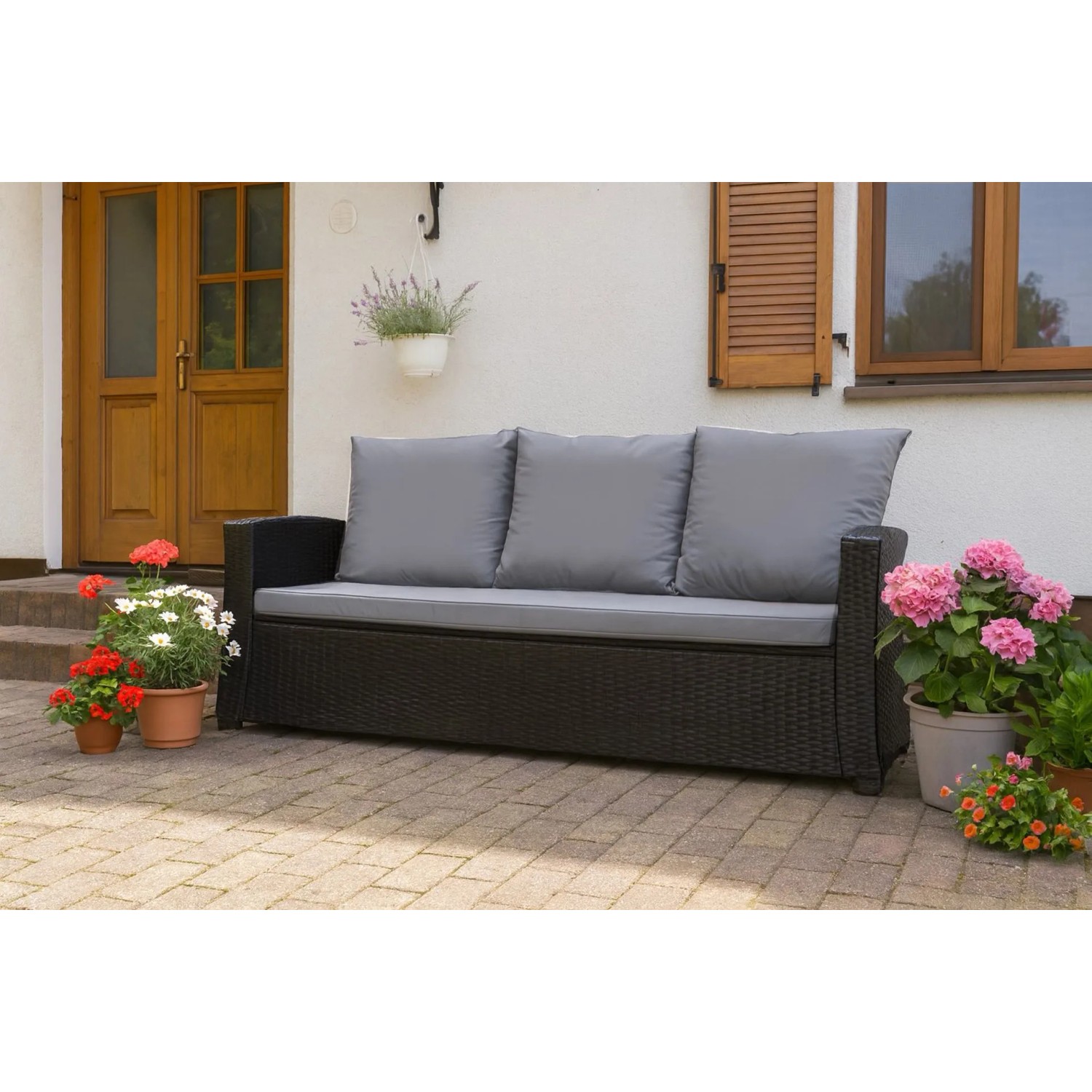 Graues Gartenkissen-Set für ein 2-Sitzer Polyrattan-Sofa im Garten.