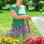 Frau bewässert Blumen mit Gardena Bewässerungsbrause im Garten.