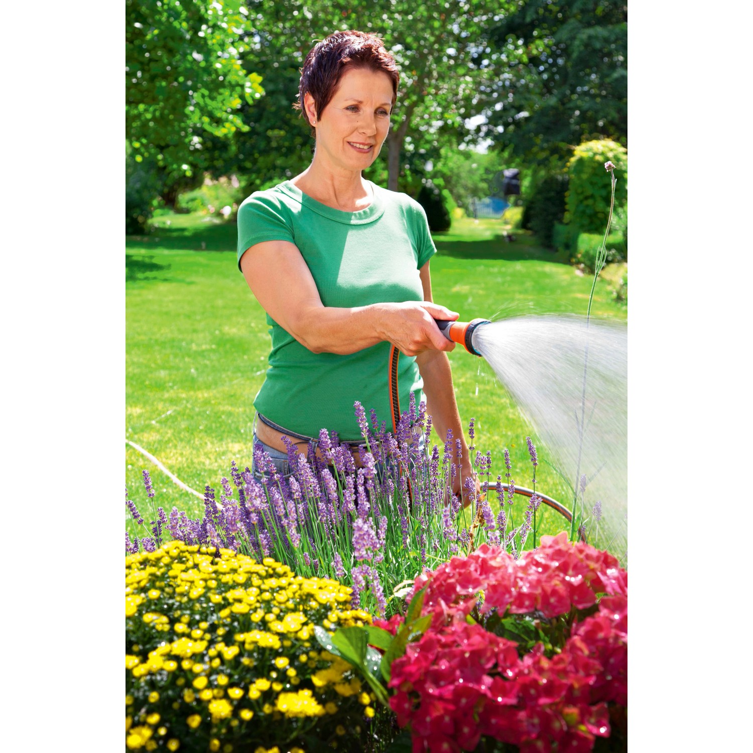 Frau bewässert Blumen mit Gardena Bewässerungsbrause im Garten.