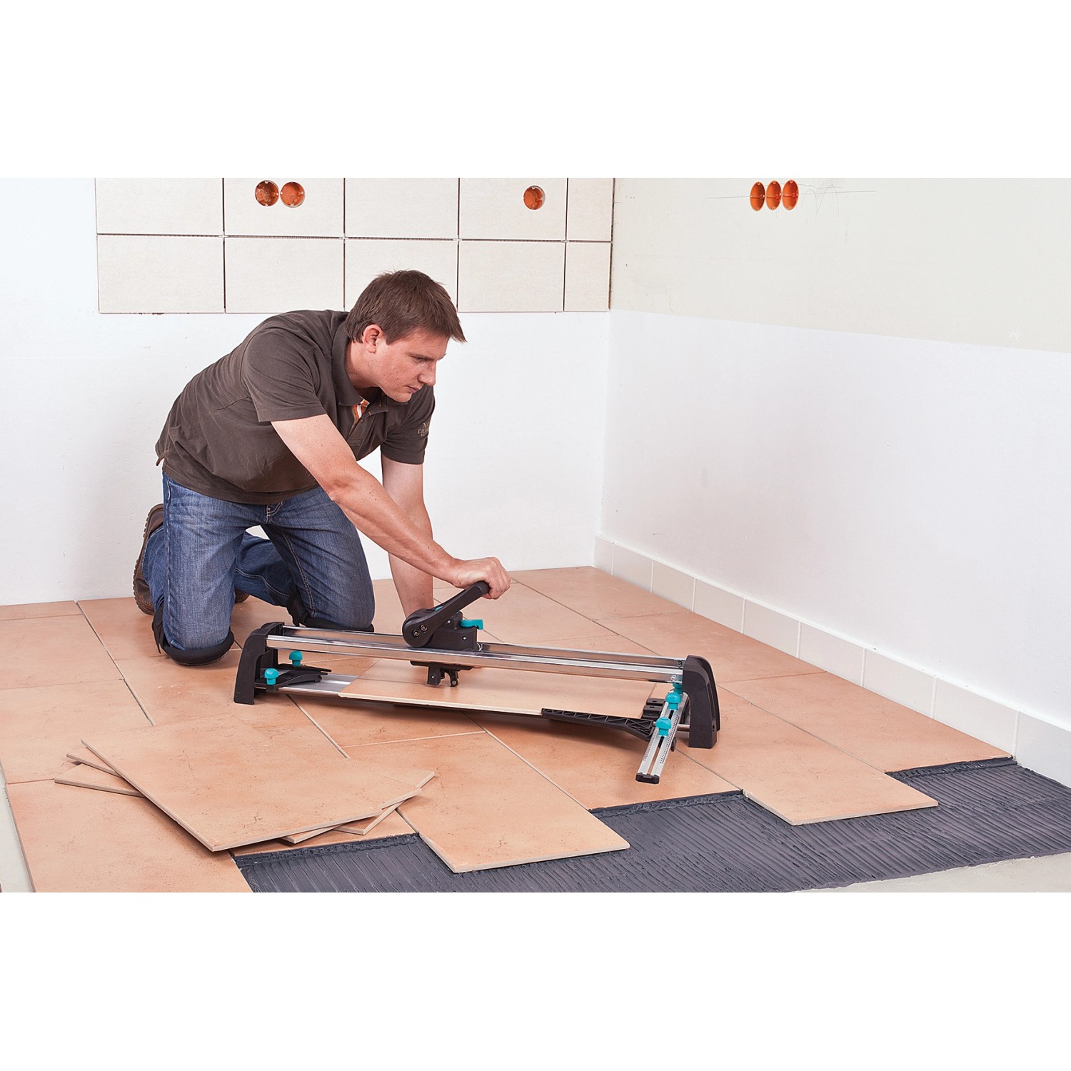 Mann schneidet Fliese mit wolfcraft Fliesenschneider TC 670 Expert. Maurerwerkzeug im Einsatz.