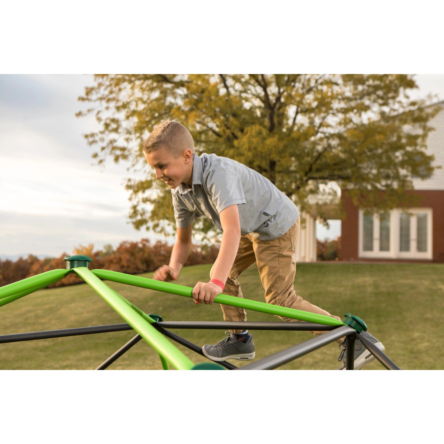 Kind klettert auf Lifetime Geodome Klettergerüst (335x168cm) im Garten. Spielturm für Spaß und Motorik.