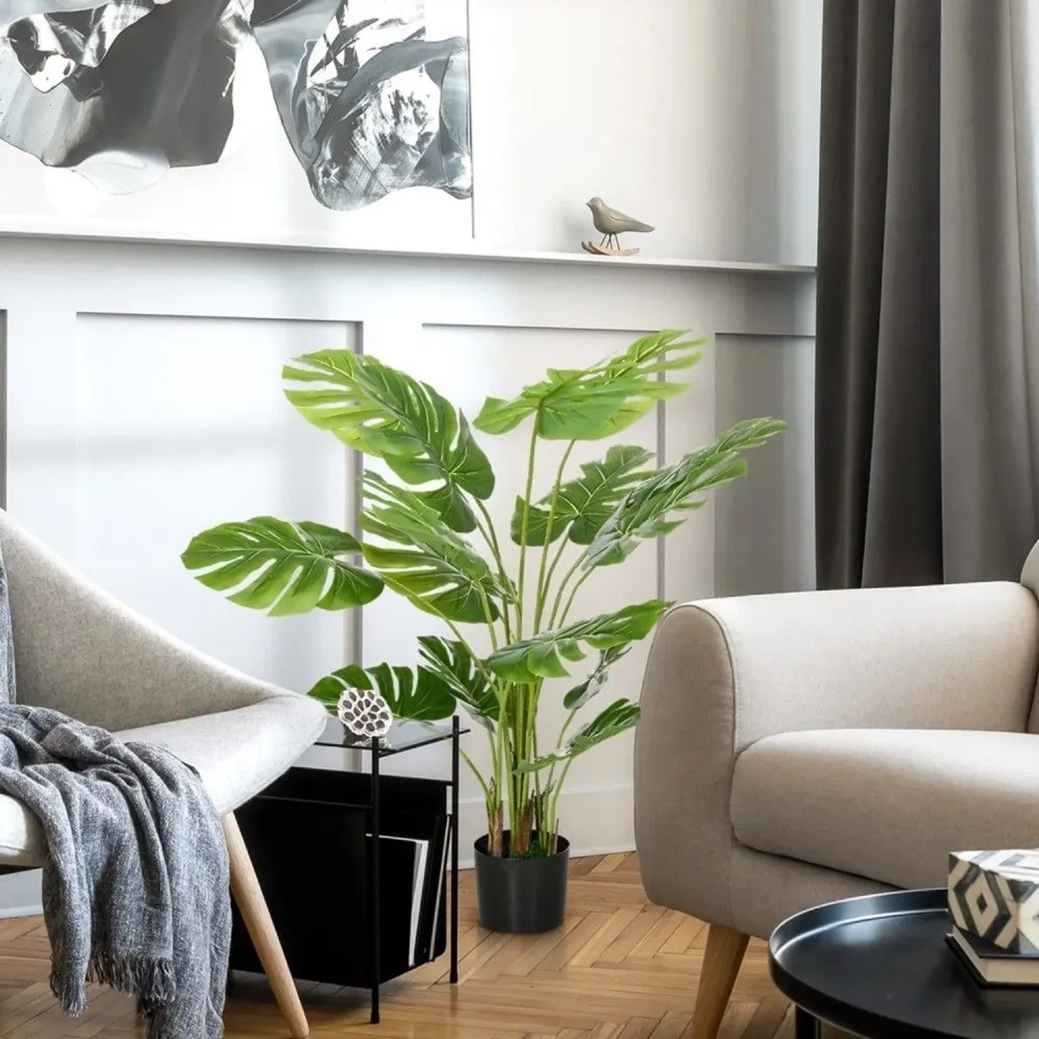 Künstliche Pflanze 120 cm mit großen grünen Blättern im schwarzen Topf, als Hausbaum im modernen Wohnzimmer.