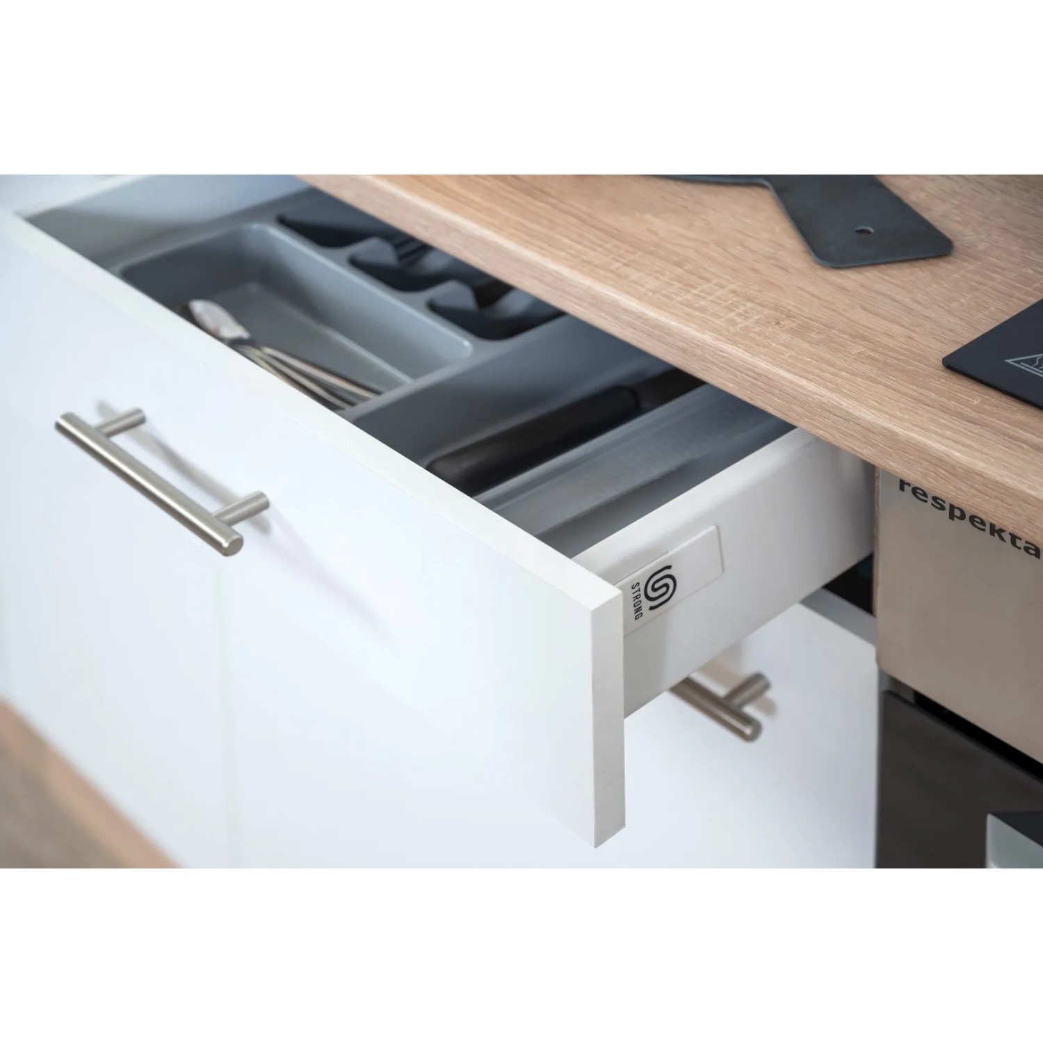 Offene Schublade der Respekta Küchenzeile in Weiß und Eiche Sägerau mit Besteckkasten.