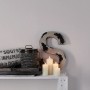 Beige Vliestapete Loop Uni von A.S. Creation, kombiniert mit Deko-Elementen auf einem weißen Regal.