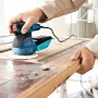 Bosch Professional GEX 125-1 AE Exzenterschleifer in Aktion auf Holz, mit Staubbox und Koffer.