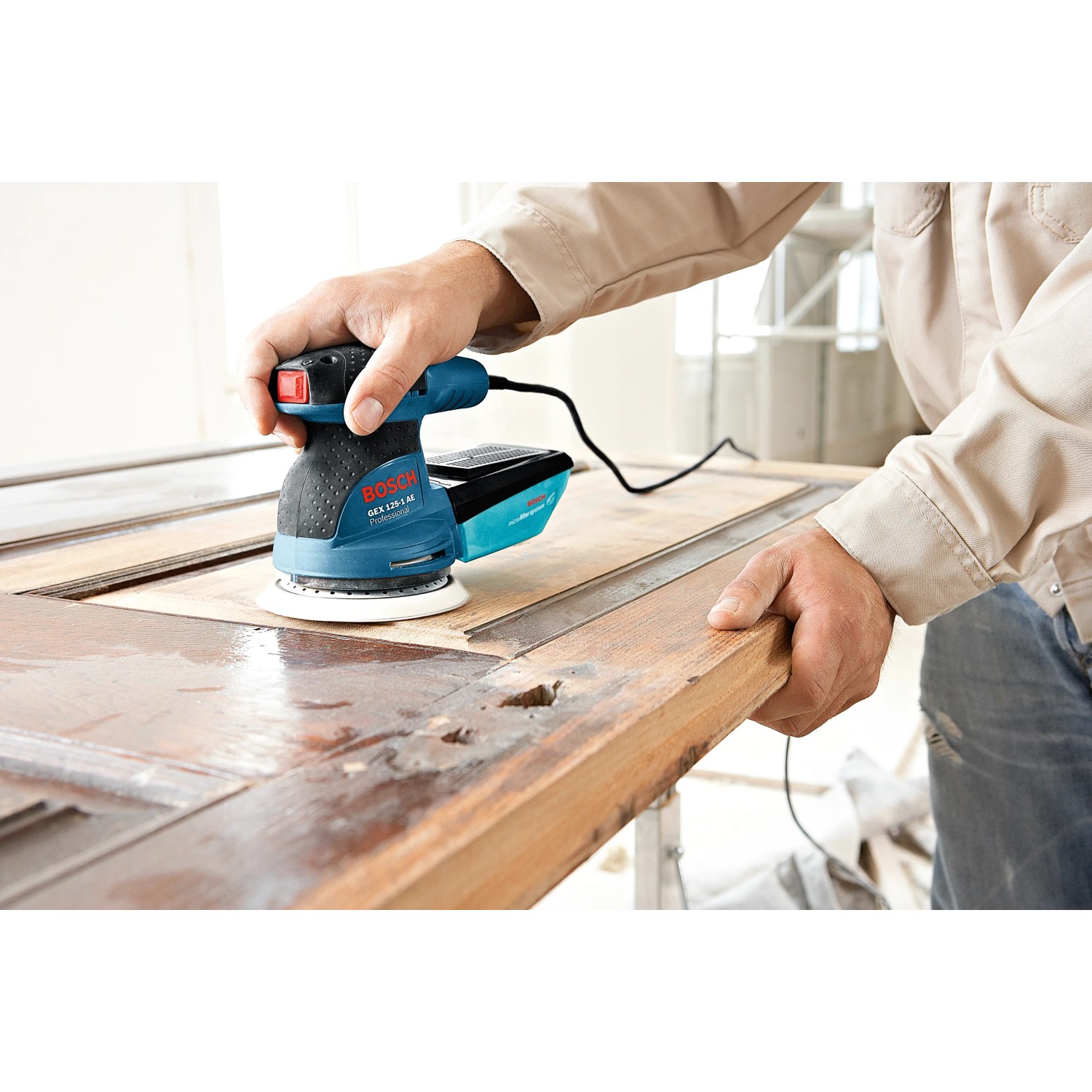 Bosch Professional GEX 125-1 AE Exzenterschleifer in Aktion auf Holz, mit Staubbox und Koffer.