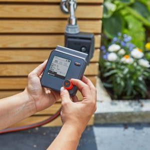 Gardena Select Bewässerungscomputer in Bedienung am Wasserhahn für automatische Gartenbewässerung.