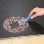 Wenko Reinigungsschaber Expert im Einsatz auf einem Glaskeramik-Kochfeld mit hartnäckigen Verkrustungen.