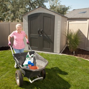 Lifetime Gerätehaus Fox, anthrazit-grau, 4,5 m² mit Schubkarre im Garten.