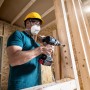 Handwerker bohrt mit Bosch Expert Flachfräsbohrer Loch in Holzkonstruktion.