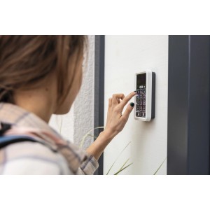 Frau bedient weiße Abus Bluetooth-Tastatur Hometec Pro CFT3100 zur Türsicherung.