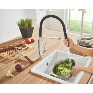 Grohe Concetto Spültischarmatur mit Chrom-Finish und schwarzem Silikonschlauch beim Gemüsewaschen.