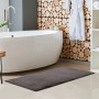 Grauer Lalee Badteppich Heaven, 40x60 cm, im Badezimmer mit Badewanne und Dekoration.