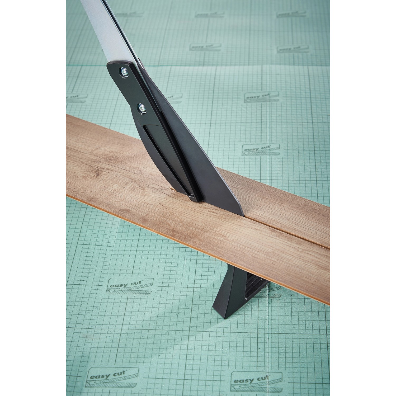 wolfcraft Vinyl- und Laminatschneider VLC 800 schneidet Laminat auf grüner Unterlage.