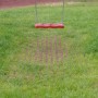 Rote Rasengitter Fallschutzplatte 100x100 cm unter einer Schaukel auf einem Spielplatz.