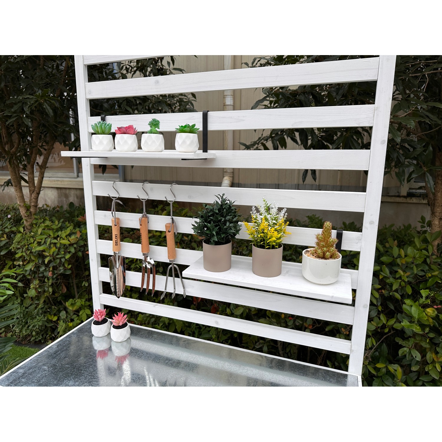 Weißes Leco Gartenregal Thea mit Ablagen und Haken für Gartengeräte und Pflanzen.