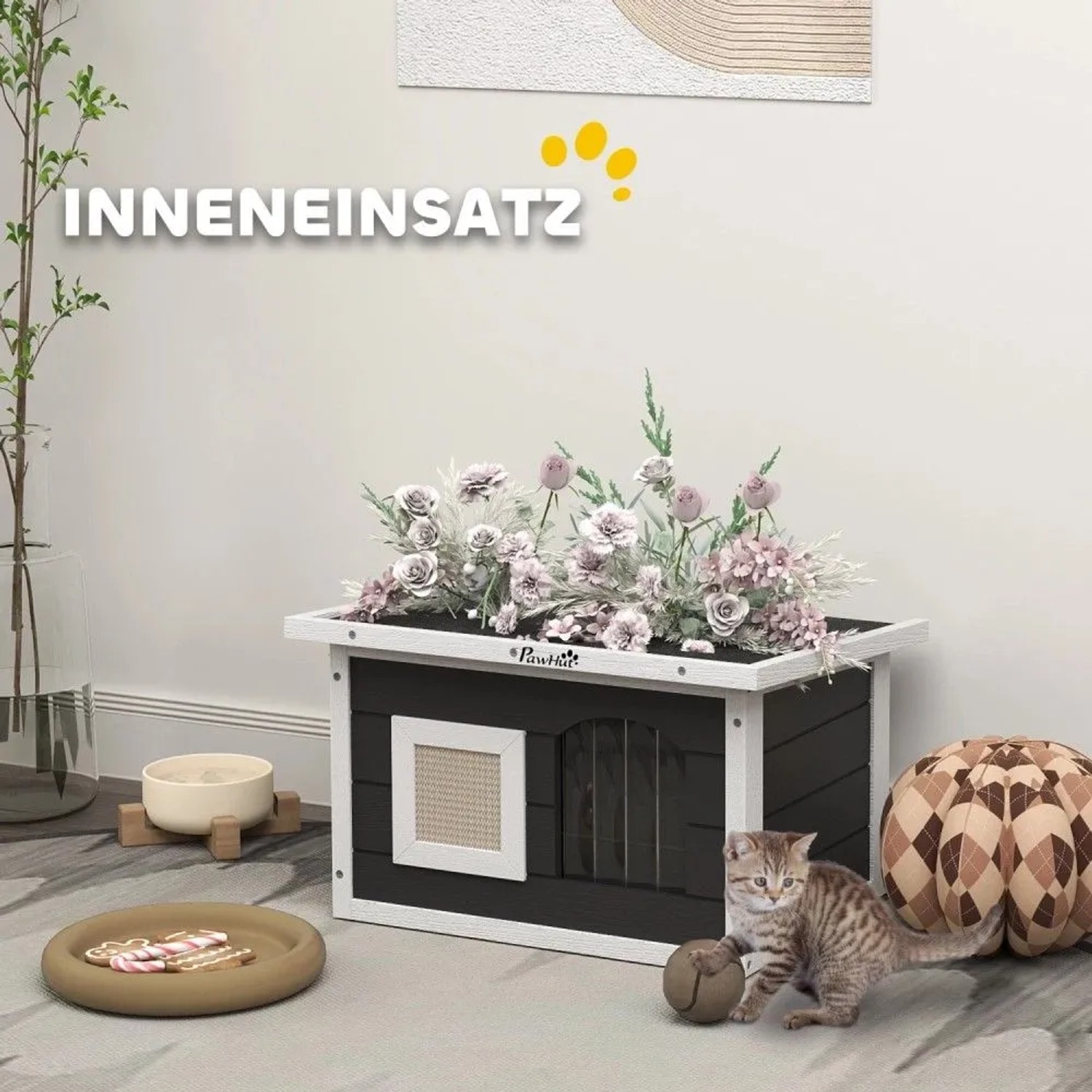 PawHut Katzenhaus grau/weiß aus Tannenholz mit Sisal-Kratzmatte, Blumen auf dem Dach. Katze spielt davor im Innenbereich.