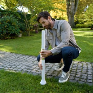 Mann installiert ECOVACS Navigations-Beacon für GOAT Mähroboter im Garten.
